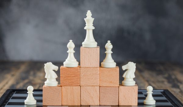 business hierarchy concept with chessboard figures pyramid wooden blocks foggy wooden table side view scaled