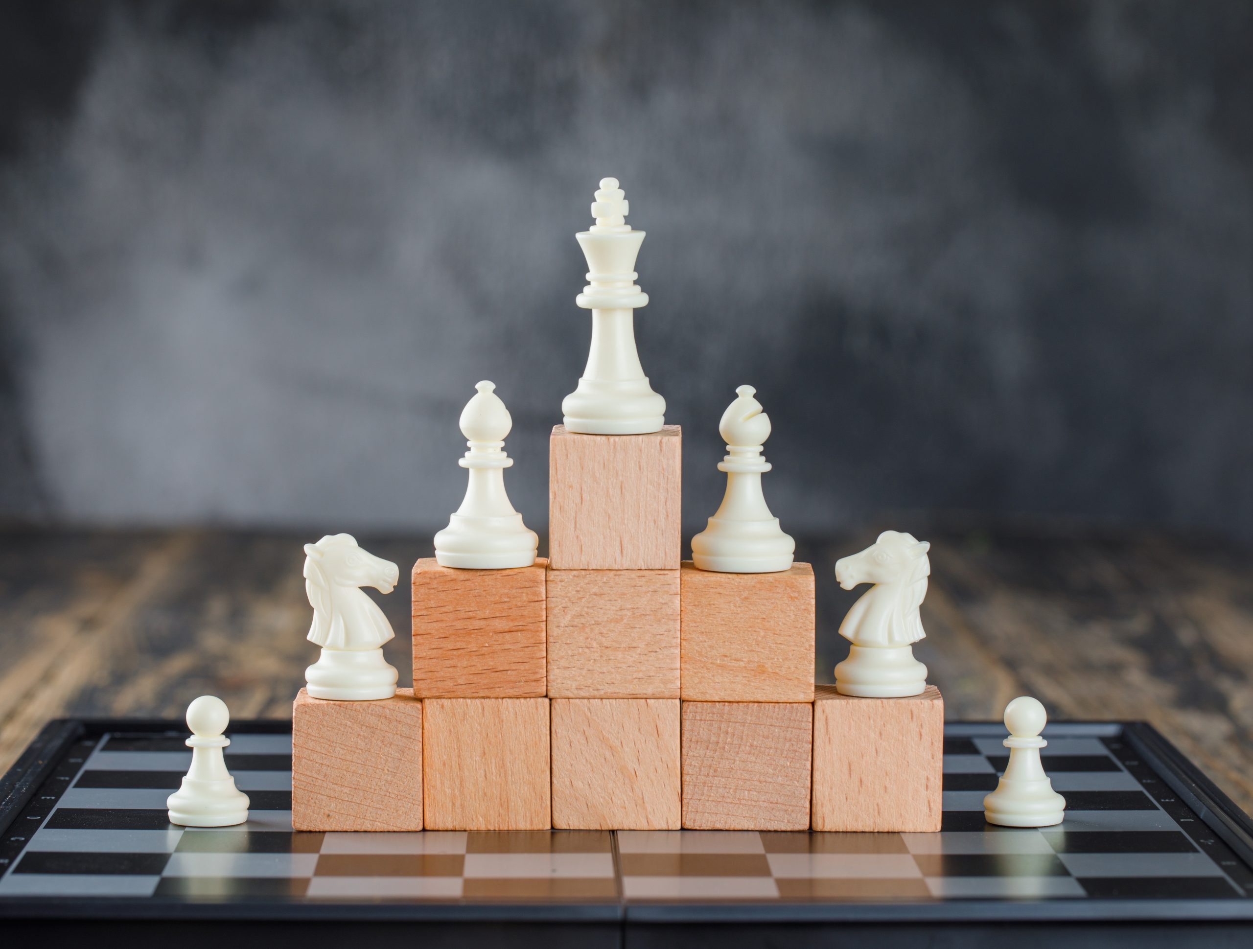 business hierarchy concept with chessboard figures pyramid wooden blocks foggy wooden table side view scaled